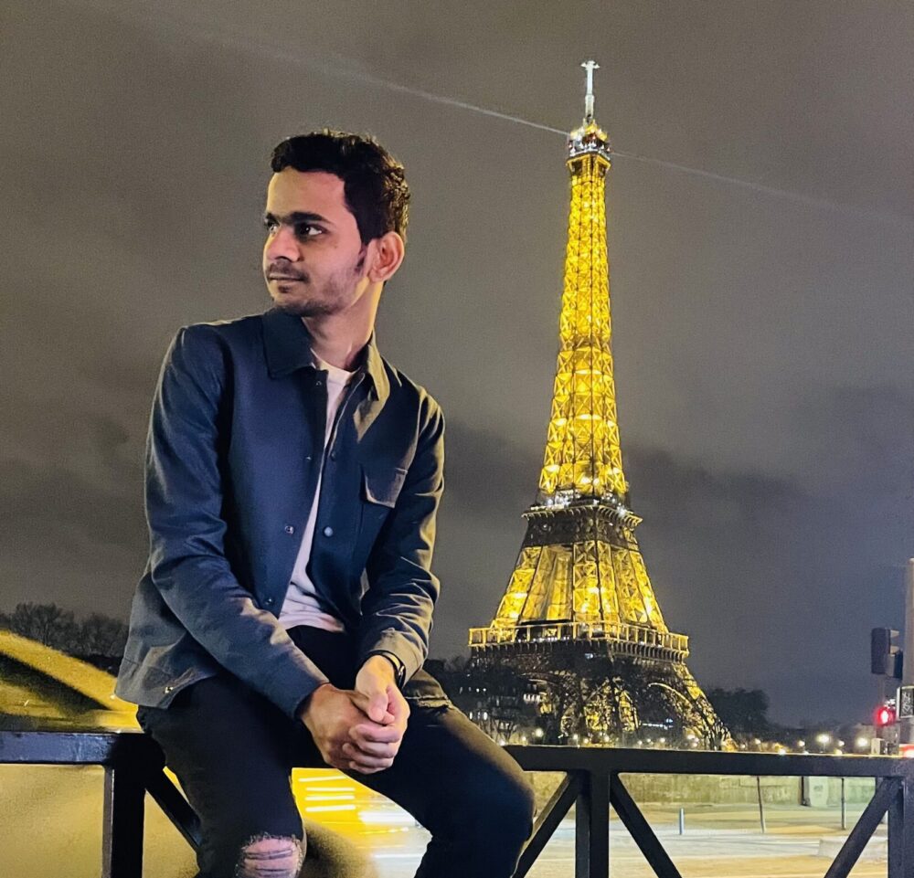 Manan sitting by the Eiffel Tower in Paris